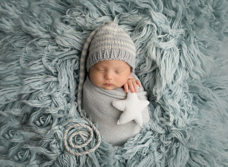 Newborn studio session with Jillian Wilhelm Photography in Windsor Ontario Canada on light sky blue flokati with stocking cap and star prop