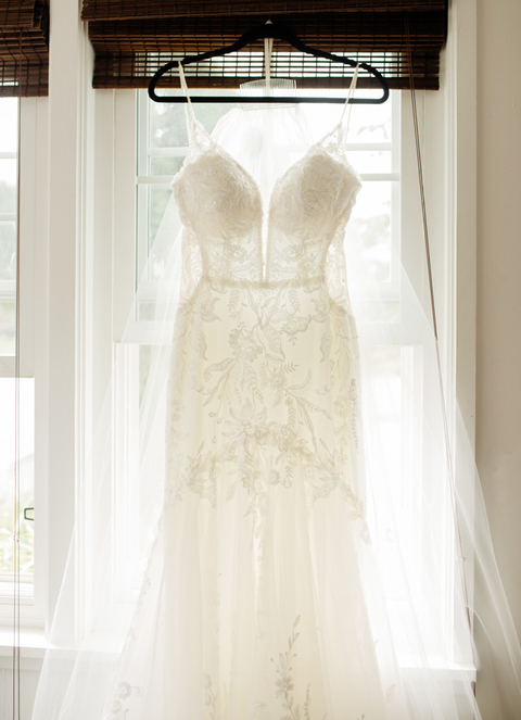 bridal gown hanging in window on wedding day 